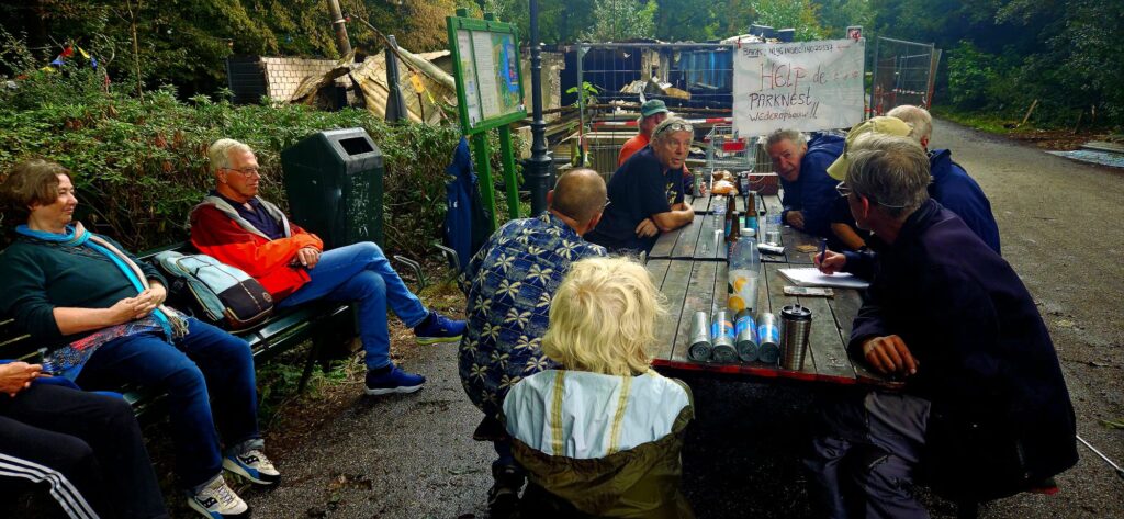 Vrijwilligers van ParkNest overleggen aan een picknicktafel voor het afgebrande gebouw